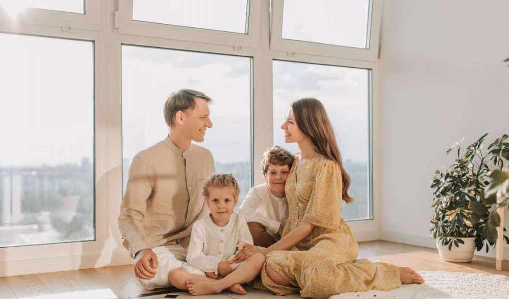 A joyful family sits together in a sunlit living room, fostering warmth and connection.