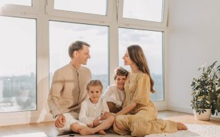 A joyful family sits together in a sunlit living room, fostering warmth and connection.
