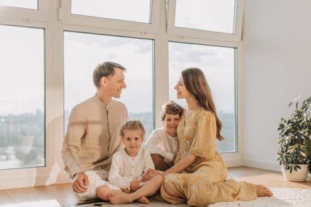 A joyful family sits together in a sunlit living room, fostering warmth and connection.